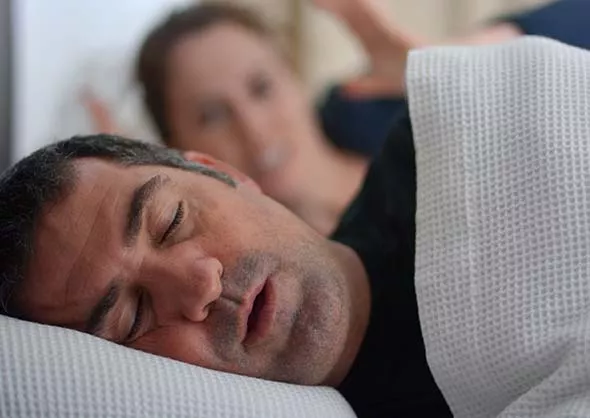 Man snoring with frustrated partner in the background