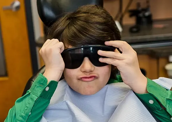 Young dental patient trying on protective eyewear