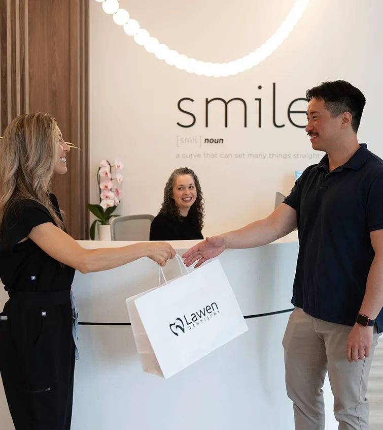Hygienist passing a bag with toothbrush and toothpaste to happy patient at mumford road clinic