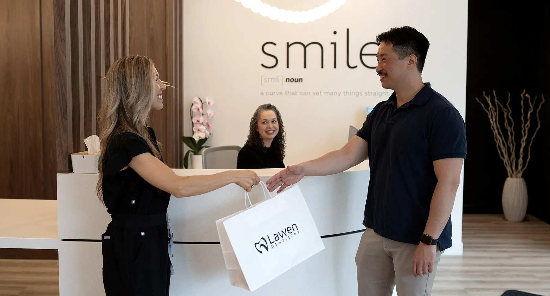 Hygienist passing a bag with toothbrush and toothpaste to happy patient at mumford road clinic