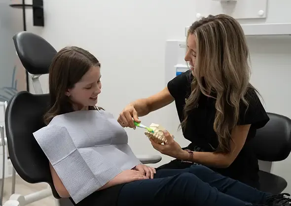 Dental Hygienist demonstrating proper brushing technique to a young patient